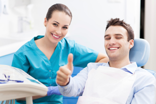 A man giving a thumbs up at a dental office.