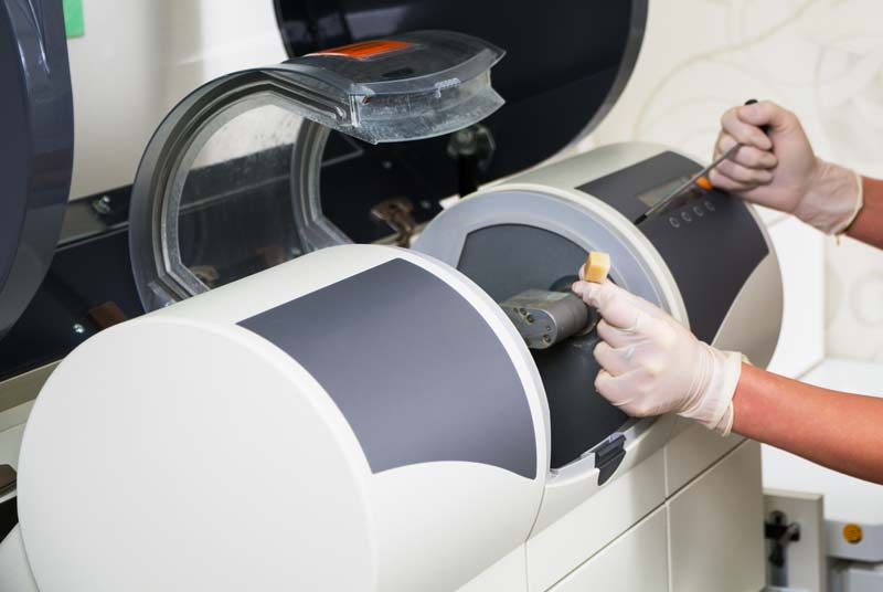 Hands prepping a CEREC machine.