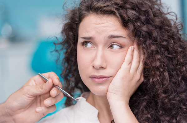 Woman holding cheek due to tooth ache that probably needs a tooth extraction in Mesa, AZ